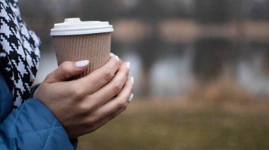 Doğada ekolojik kağıt bardaktan kahve içmek. Sıcak bir bardağı sıcak bir içecekle tutarken sıcak eller, sakinleşmek için yürüyüş..