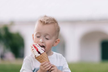 Küçük bir çocuğun portresi. Bir bebek lezzetli bir dondurma külahı yer. Mutlu çocuk. Yaz günü
