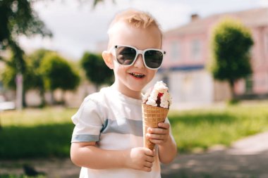 Küçük bir çocuğun portresi. Bir bebek lezzetli bir dondurma külahı yer. Mutlu çocuk. Yaz günü