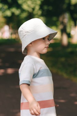 Panamalı mutlu bir çocuk ağaçların gölgesinde bir yaz parkında oynuyor..