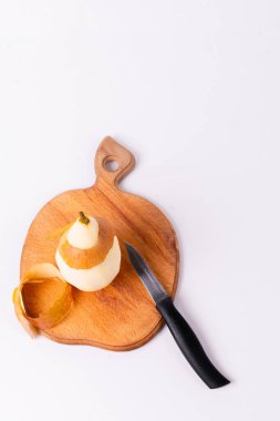 Bir armut, tahta bir kesme tahtasına saplanmış bir bıçakla soyuluyor..