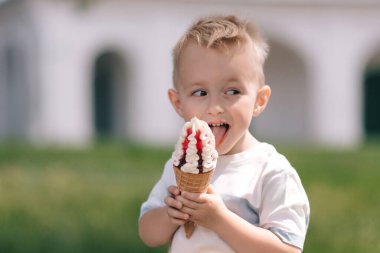 Küçük bir çocuğun portresi. Bir bebek lezzetli bir dondurma külahı yer. Mutlu çocuk. Yaz günü