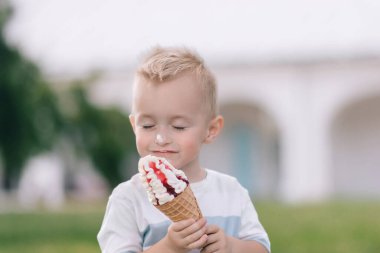 Küçük bir çocuğun portresi. Bir bebek lezzetli bir dondurma külahı yer. Mutlu çocuk. Yaz günü