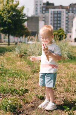 Küçük bir çocuğun portresi. Bir bebek lezzetli bir dondurma külahı yer. Mutlu çocuk. Yaz günü