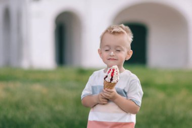 Küçük bir çocuğun portresi. Bir bebek lezzetli bir dondurma külahı yer. Mutlu çocuk. Yaz günü