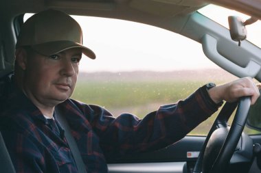 Şapka takan bir adam araba sürüyor, ana konuya ve görüntünün hareketine odaklanıyor..