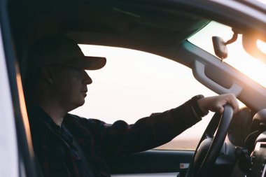 Şapkalı bir adam araba sürer..