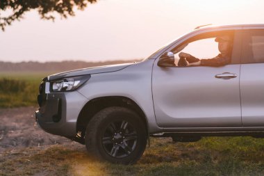 Gümüş bir kamyon çimlerle kaplı bir arazide park halinde..