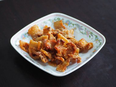 Tayland yemeği, kızarmış domuz eti, kavrulmuş kızarmış domuz eti, koyu tahıllı arka planda izole edilmiş beyaz tabakta yakın plan..