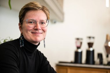 Belçika 'da siyah forma giyen 36' lı yaşlarda kısa saçlı beyaz bir kadının kapalı bir portresi.