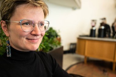 Belçika 'da siyah forma giyen 36' lı yaşlarda kısa saçlı beyaz bir kadının kapalı bir portresi.