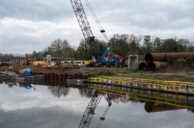 Erembodegem, Doğu Flaman Bölgesi, Belçika, 11 04 2022 - Dender Nehri 'ne yansıyan bir limanın sanayi vinçleri ve kargo konteynerleri