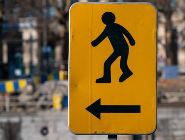 Molenbeek, Brüksel Başkent Bölgesi, Belçika - 12 17 2022 - Sarı arka planda bir inşaat alanında yürümenin güvenli yolunu gösteren imza