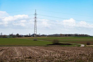 Cropped agriculture soil, green farmland and a high voltage electricity pool, Relegem, Flemish Brabant Region, Belgium