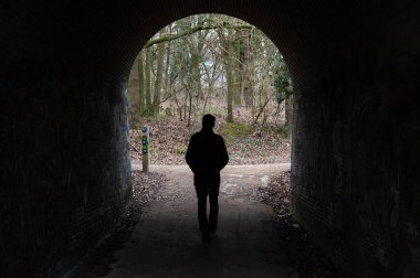 Uccle, Brüksel Başkent Bölgesi, Belçika, 4 Mart 2023 - Kemerli bir köprünün altında yürüyen yalnız adam