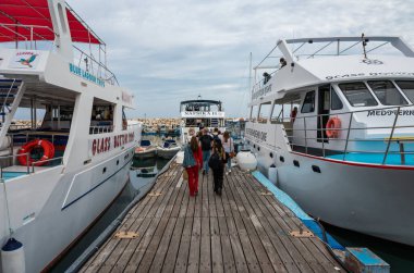 Latsi, Poli Crysochous, Kıbrıs, 22 Mart 2023 - Turistler iki gezi gemisiyle ahşap akranlarına doğru yürüyorlar