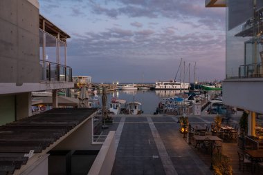Limasol, Kıbrıs - 23 Mart 2023 - Yansıyan tekne, bina ve renkli gece ışıklarıyla eski limana bakın