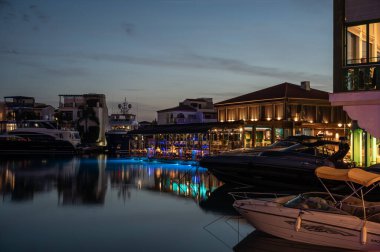 Limasol, Kıbrıs - 23 Mart 2023 - Yansıyan tekne, bina ve renkli gece ışıklarıyla eski limana bakın