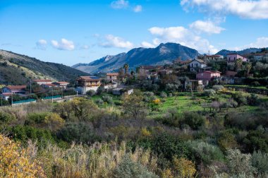 Cannizaro çevresindeki evler ve mavi gökyüzü ile engebeli dağların panoramik manzarası. Favare, Sicilya, İtalya
