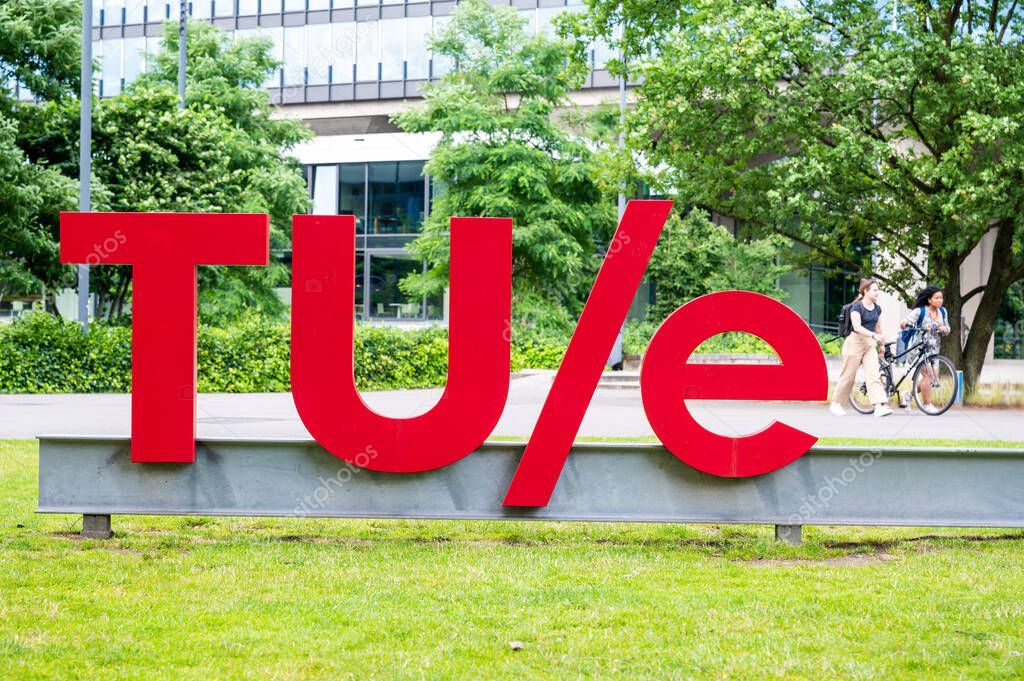 Eindhoven, North Brabant, The Netherlands, July 10, 2024 - Female students passing by the sign of the Technical University Eindhoven TUE