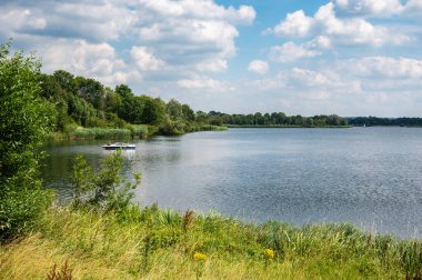 Linden, Gelderland, Hollanda, 11 Temmuz 2024 - Maas nehrinin yeşil kıyısında bir tekne