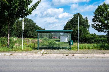 Wietmarchen, Lower Saxony, Almanya, 14 Temmuz 2024 - Otobüs durağı barınağı ve kırsal bölgedeki asfalt yol