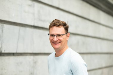 Brüksel, Belçika 'da gri bir duvara yaslanmış 45' lik beyaz bir adamın portresi. model bırakıldı