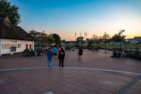 stock image Dahme, Germany, July 20, 2024 - Teenage tourists walking at the dyke and square during sunset in summer holidays