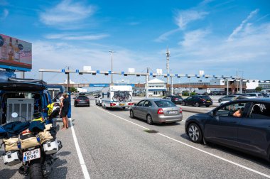 Fehmarn - Puttgarden, Almanya, 21 Temmuz 2024 - Danimarka feribotuna binmek için bekleyen arabalar, kampçılar ve motorsikletler