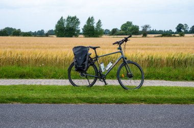 Stroby, Seeland, Denmark, July 23, 2024 - Trekking bike with paniers and golden agriculture field clipart