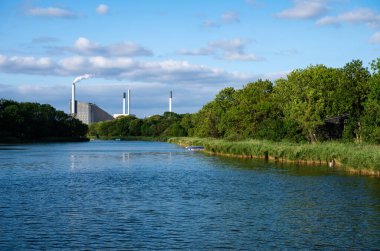 Kopenhag, Danimarka, 24 Temmuz 2024 - Körfezde yeşil bankalar ve arka planda endüstriyel faaliyet