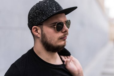 Şapkalı ve güneş gözlüklü bir adam gri arka planda poz veriyor, Brüksel, Belçika. Model bırakıldı