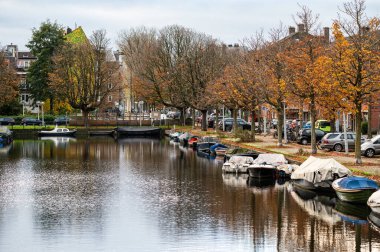 Renkli sonbahar ağaçları ve Amsterdam, Hollanda 'daki Rijpgracht' a yansıyan küçük tekneler, NOV 15, 2024