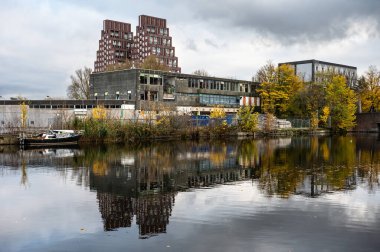 Evler, terk edilmiş sanayi ve tekneler Amsterdam, Hollanda, NOV 15, 2024 'teki Batı pazar kanalına yansıyor.