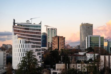 Tiran, Arnavutluk, DEC 7, 2024 'te alacakaranlıkta renkli apartman blokları ve dağların yüksek açılı manzarası