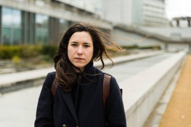 Açık havada, şehirde uzun bir merdivende oturan kahverengi saçlı 28 yaşında beyaz bir kadının portresi. Model bırakıldı