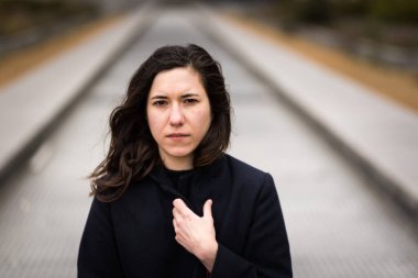 Açık havada, şehirde uzun bir merdivende oturan kahverengi saçlı 28 yaşında beyaz bir kadının portresi. Model bırakıldı