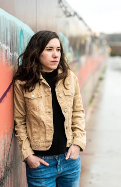 Çekici bir esmerin, şehrin renkli bir duvarına karşı poz verirken yarı vücut pozu. Model bırakıldı