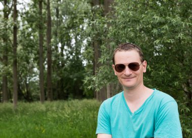 Portrait of a 41 yo white man with pilote sunglasses and a green nature background, Flemish Brabant, Belgium. Model released clipart