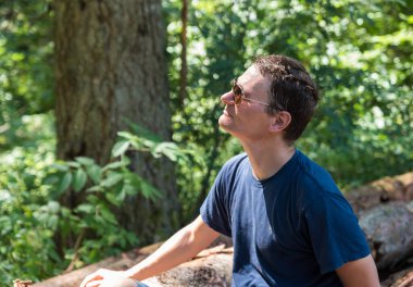 Portrait of an active 40 yo man, sitting on tree trunks in the woods, Burg-Reuland, Belgium. Model released clipart