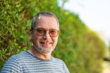 49 yaşındaki gözlüklü ve sakallı bir adamın portresi Ternat 'ta yeşil arka planda, Flaman Brabant, Belçika Modeli