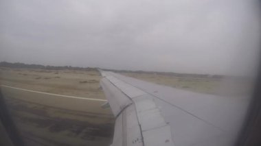 Bu video, Peru, Piura 'ya inen ticari bir uçağın son yaklaşımı sırasında çekildi. Pencere kenarından bakıldığında, uçağın kanadı aşağıdaki yerleşim alanları, binalar ve ağaçların görüldüğü şehir manzarası boyunca uzanıyor..