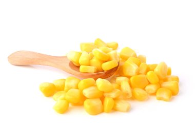Beyaz arka planda tahta kaşıkta mısır tohumları yığını.
