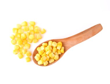 Beyaz arka planda tahta kaşıkta tatlı mısır tohumları yığını