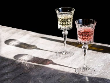 İki kristal şarap kadehi şampanya beyaz şarap ve gri arka planda gül şarabı. Sert ışıklar ve gölgeler, şarap testi konsepti. Bir restoranda kahvaltı, metin için kopyalama alanı