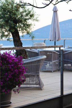 Şık bir şarap imalathanesi. Üzüm bağında saman doğal sandalye ve masalarla şarap tatma alanı, arka planda deniz manzaralı atmosferik bir yer. Şarap degukasyonu için güzel bir şarap restoranı.