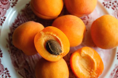 Masanın üzerindeki tabakta nefis olgun kayısılar. Bir yığın taze portakal aromalı kayısı ve İngiliz porseleni tabağında tohum olan bir kayısı..