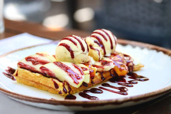 Tam tahıllı Belçika waffle 'ı, yanında da bir top dondurma ve dut sosu, yakın çekim, kopyalama alanı. Belçika waffle 'ı, dondurma, böğürtlen şurubu ve restoran masasında taze kesilmiş meyveler..