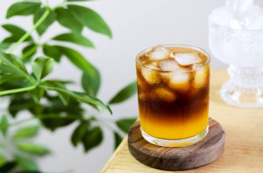 Tropikal yapraklı minimalist kahve afişi ve kopyalama alanı. Portakal suyu, espresso, karamel şurubu ve buzdan yapılmış modaya uygun kahve içeceği. Ahşap masada katmanlı kahve kokteyli.