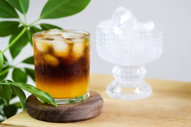 Tropikal yapraklı kahve afişi ve fotokopi alanı. Portakal suyu, espresso, karamel şurubu ve buzdan yapılmış modaya uygun kahve içeceği. Ahşap masada bir bardak katmanlı kahve kokteyli. Menü eşleşmesi